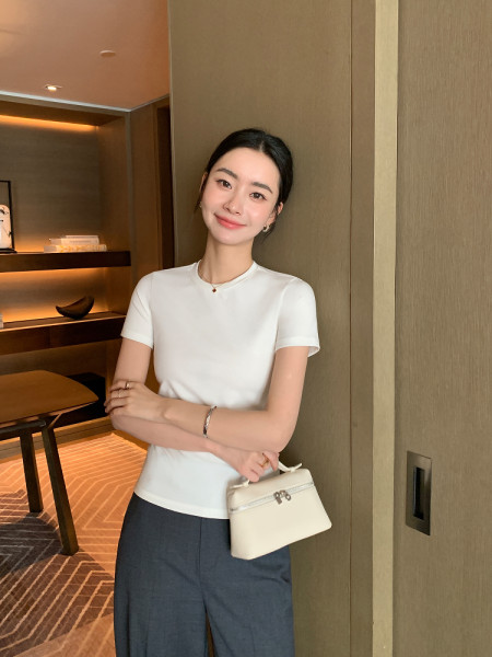 Woman wearing a white short-sleeve top and holding a small white handbag