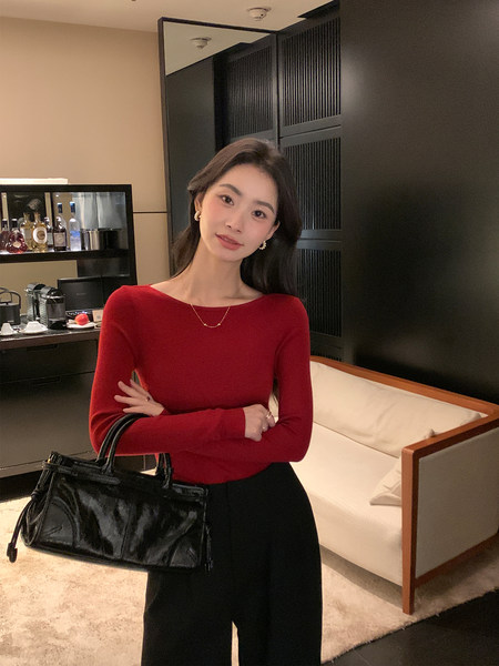 Woman wearing a red long-sleeve top with black pants and a black handbag