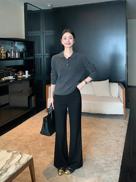 Woman wearing a dark knit top and black wide-leg pants with a black tote bag
