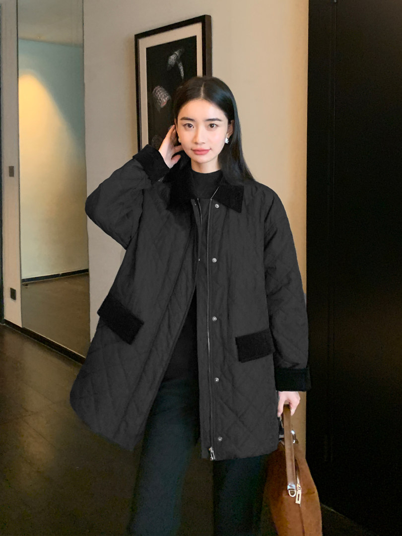 Black quilted coat worn by a woman indoors
