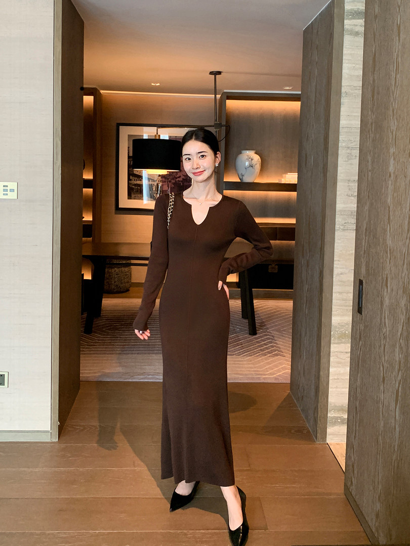Woman wearing a long brown fitted dress indoors