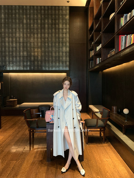 Woman wearing a long striped trench coat in a dark interior setting
