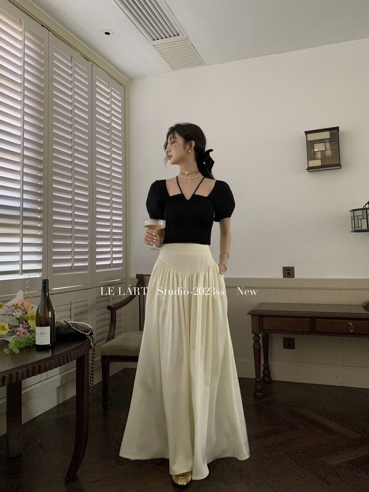 Model wearing a black puff-sleeve top with a cream maxi skirt