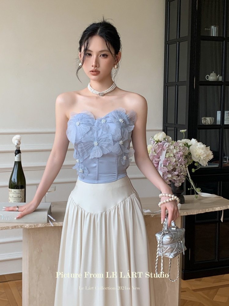 Model wearing a light blue floral strapless top with a cream maxi skirt