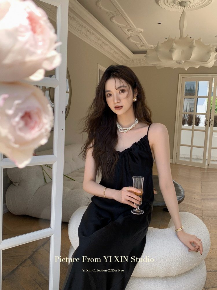 Woman wearing a black spaghetti-strap dress indoors