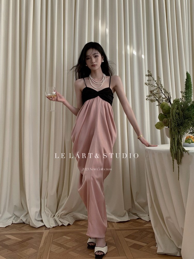 Model wearing a pink and black sleeveless dress in a studio setting