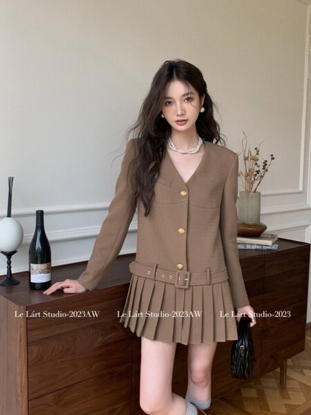 Woman wearing a brown long-sleeve belted pleated mini dress
