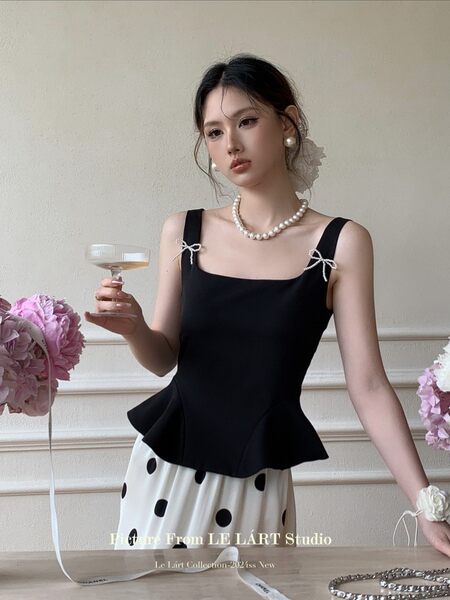 Woman wearing a black square-neck peplum top with a white polka dot skirt