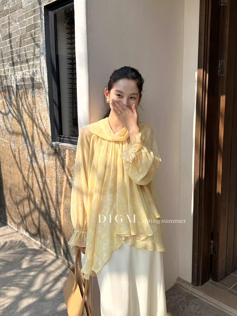 Woman wearing a sheer yellow blouse with a flowing layered design