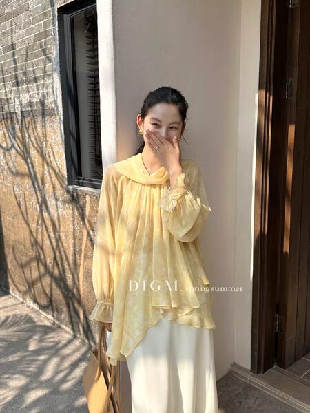 Woman wearing a sheer yellow blouse with a flowing layered design