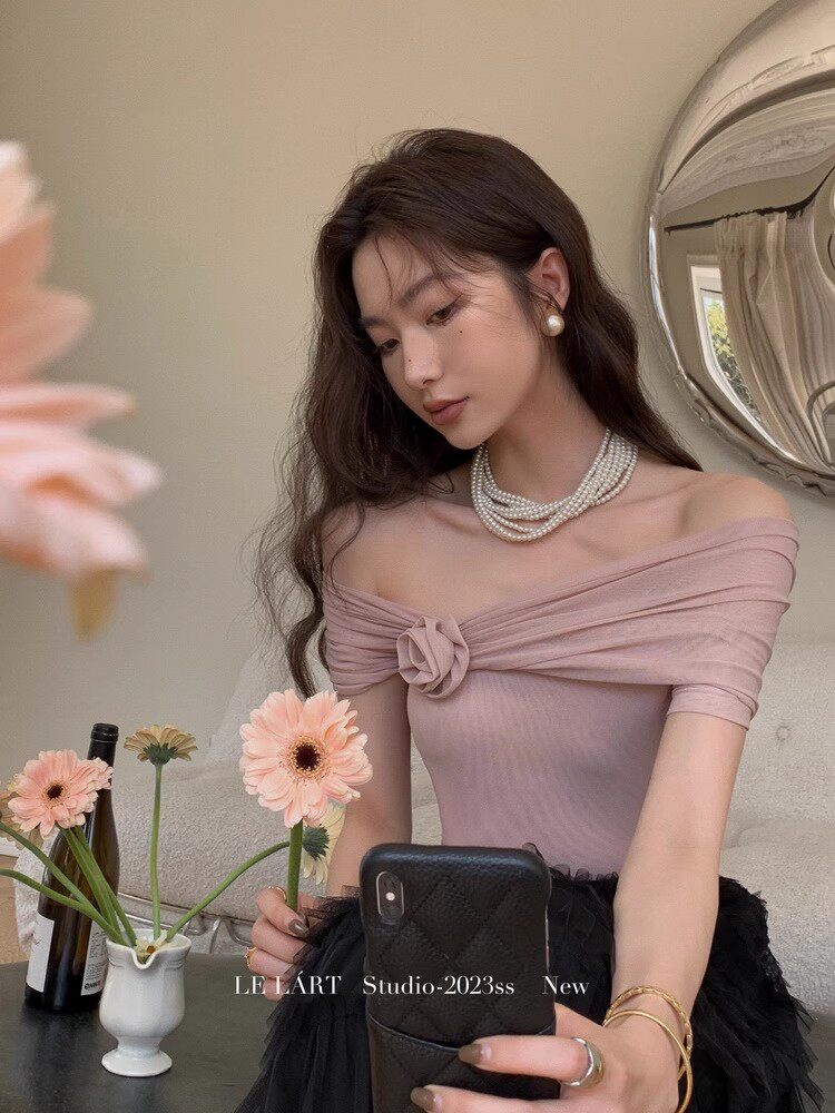 Woman wearing a pink off-shoulder fitted top with pearl jewelry