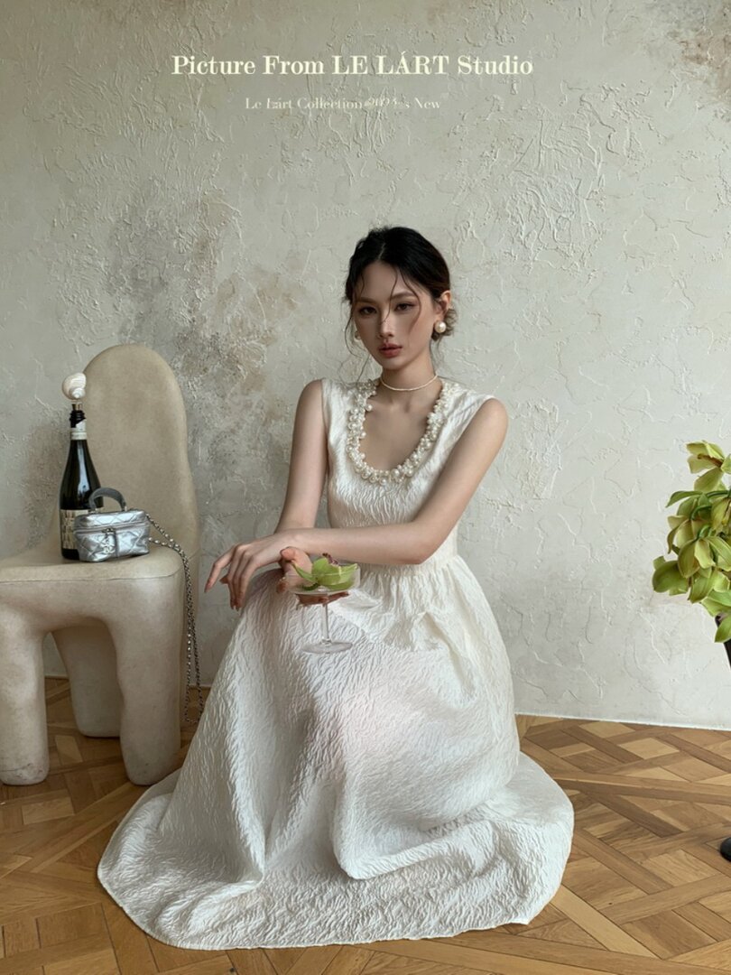 White sleeveless textured dress worn by a model in a studio setting