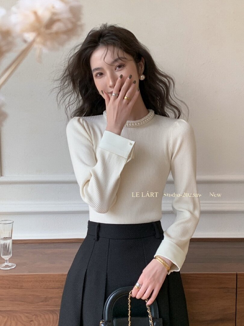 Woman modeling a cream ribbed long-sleeve top with a black high-waisted skirt