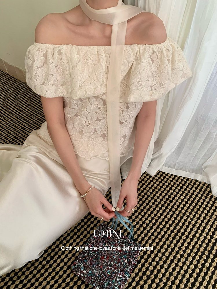 Model wearing an off-shoulder cream lace dress with a satin skirt