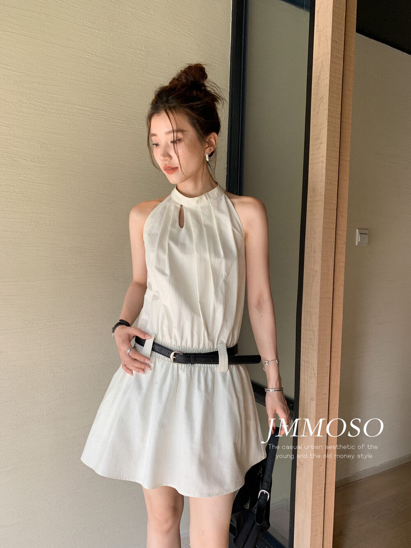 Woman wearing a cream sleeveless halter mini dress with a black belt