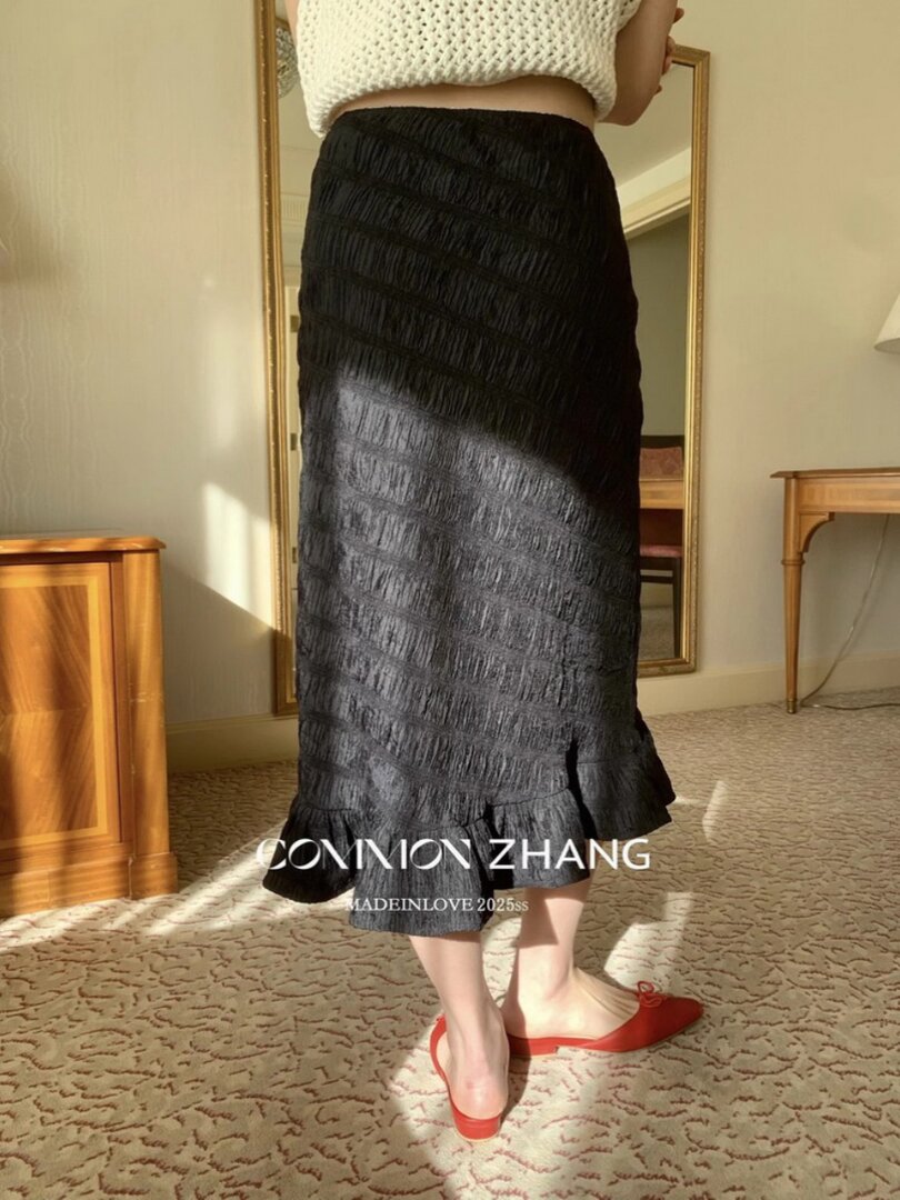 Black textured midi skirt worn with a white knit top