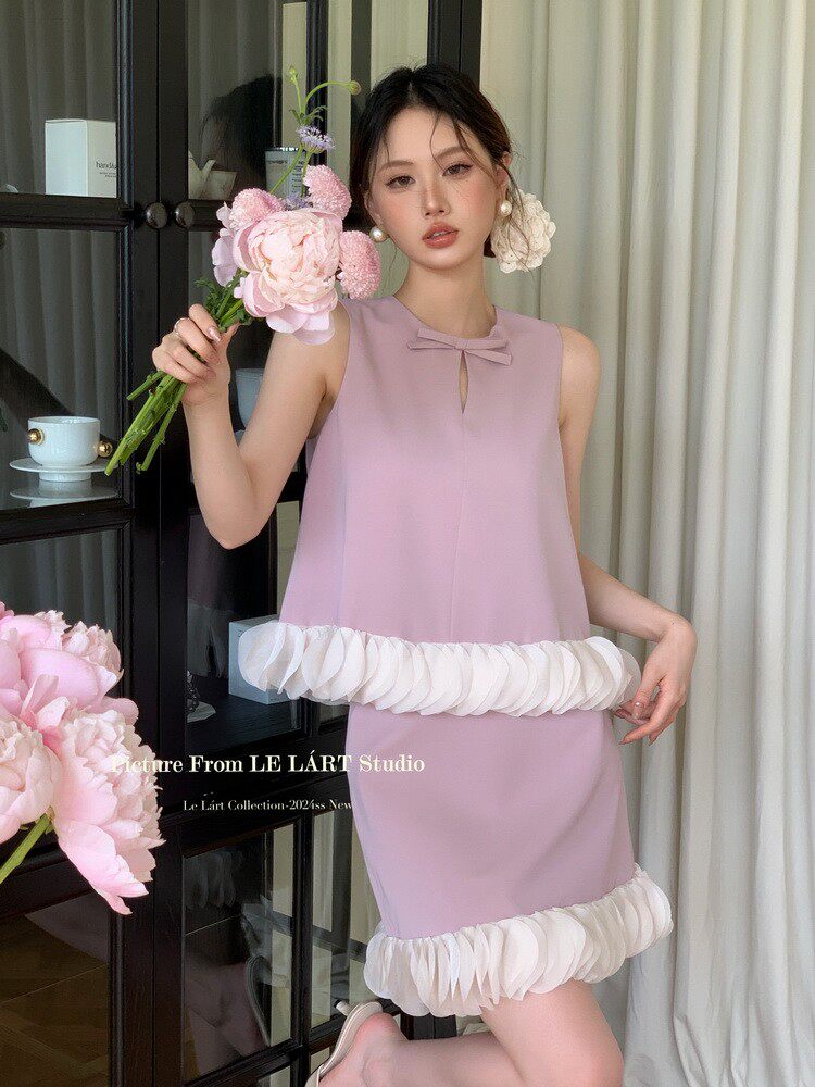 Pastel pink sleeveless dress with bow detail and ruffled hem worn by a model