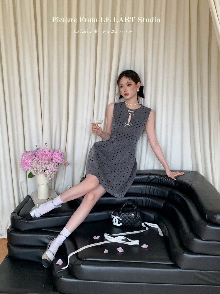 Model wearing a gray polka dot sleeveless dress with bow details
