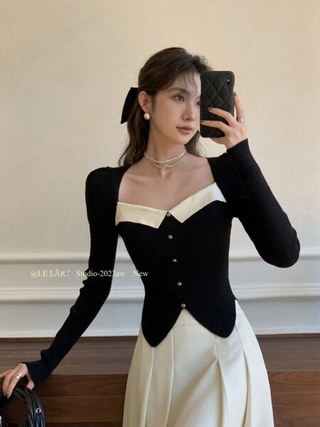 Model wearing a black-and-cream fitted knit outfit with gold buttons