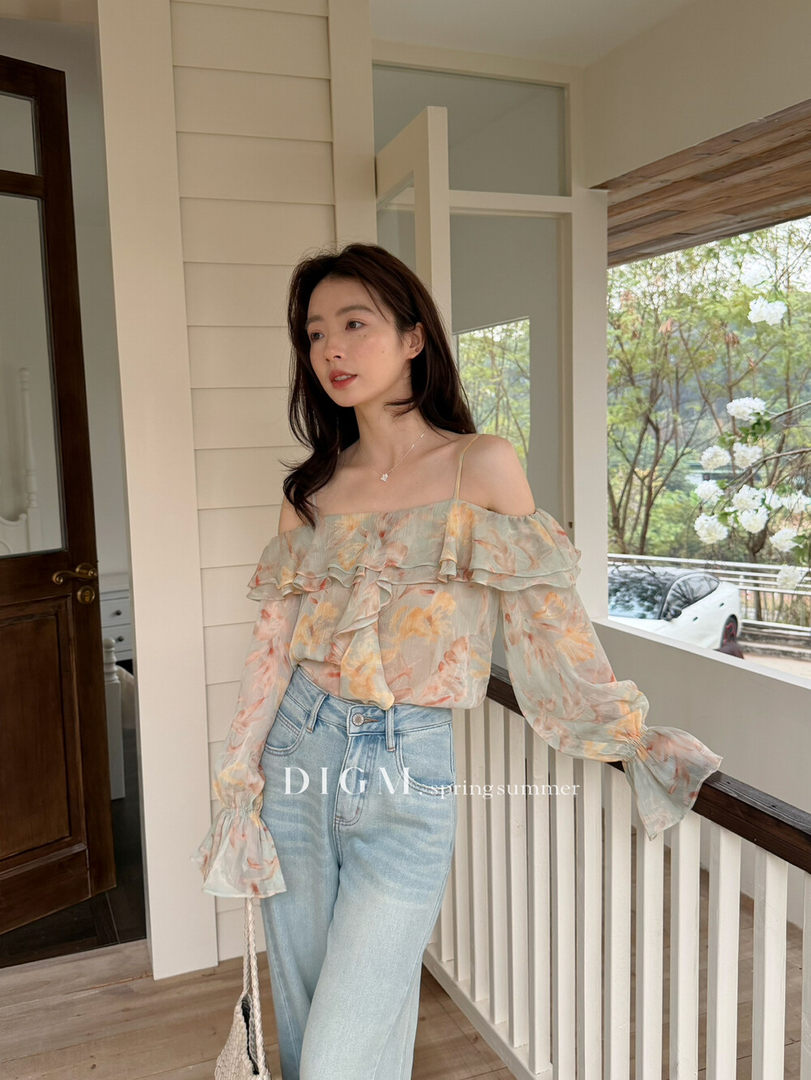 Model wearing a floral off-shoulder long-sleeve top with light wash jeans