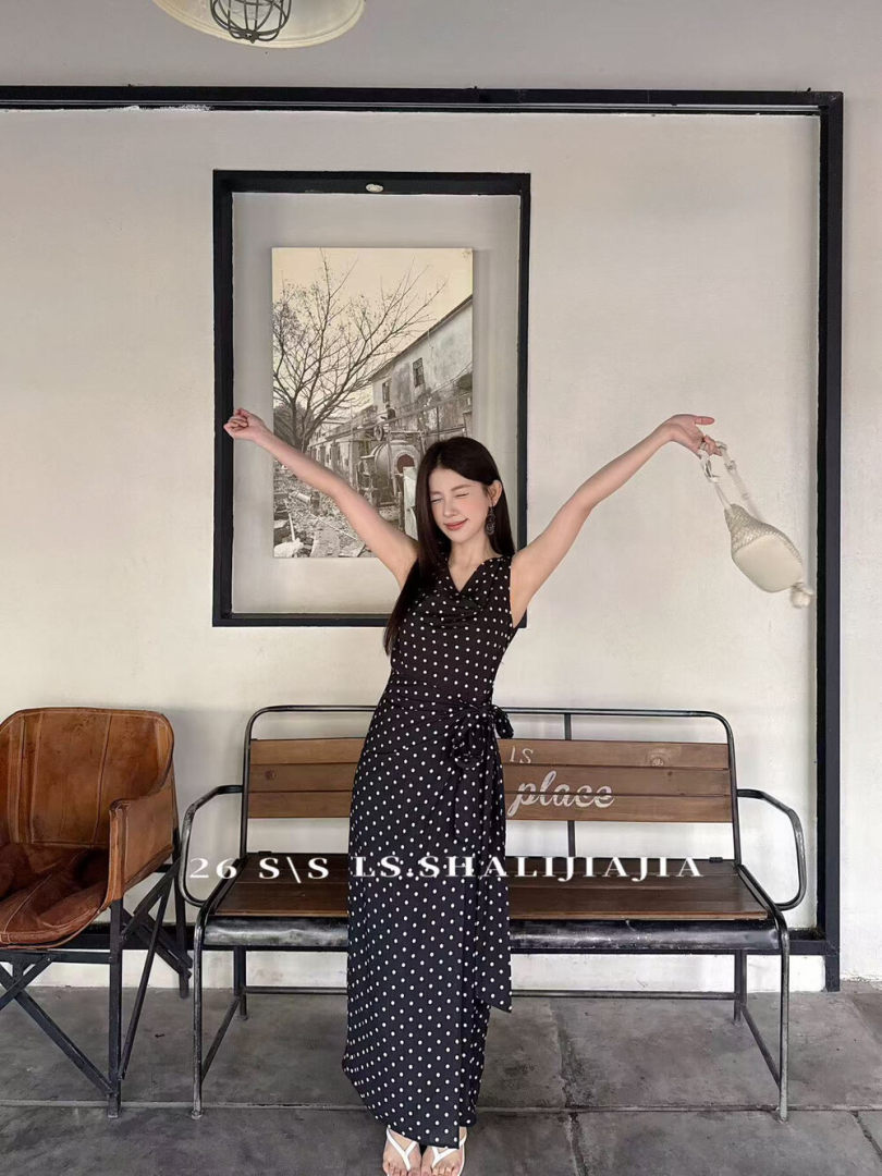 Woman wearing a black polka dot sleeveless wrap maxi dress