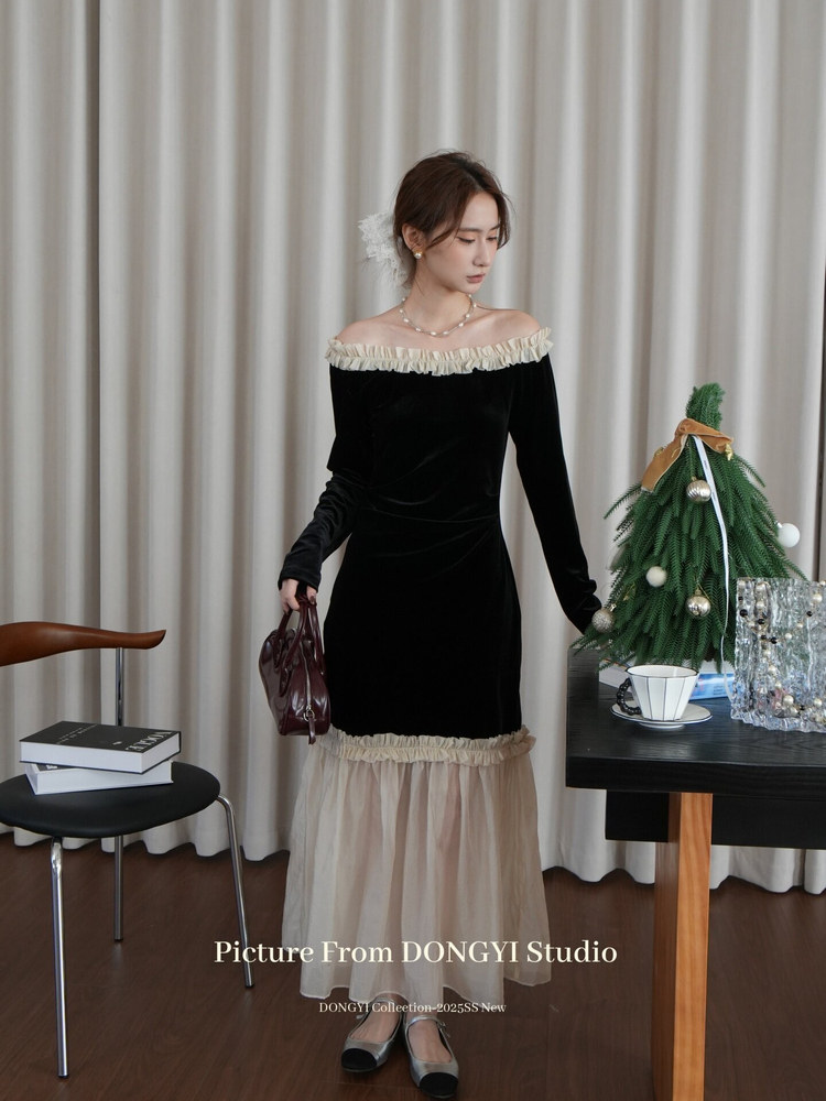 Woman wearing a black off-shoulder dress with cream ruffle trim and sheer hem