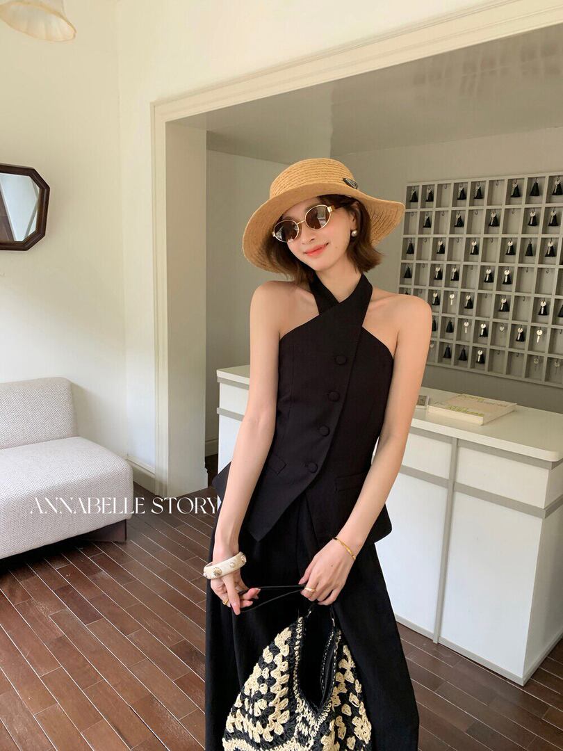 Woman wearing a black halter-style outfit with a straw hat and woven bag
