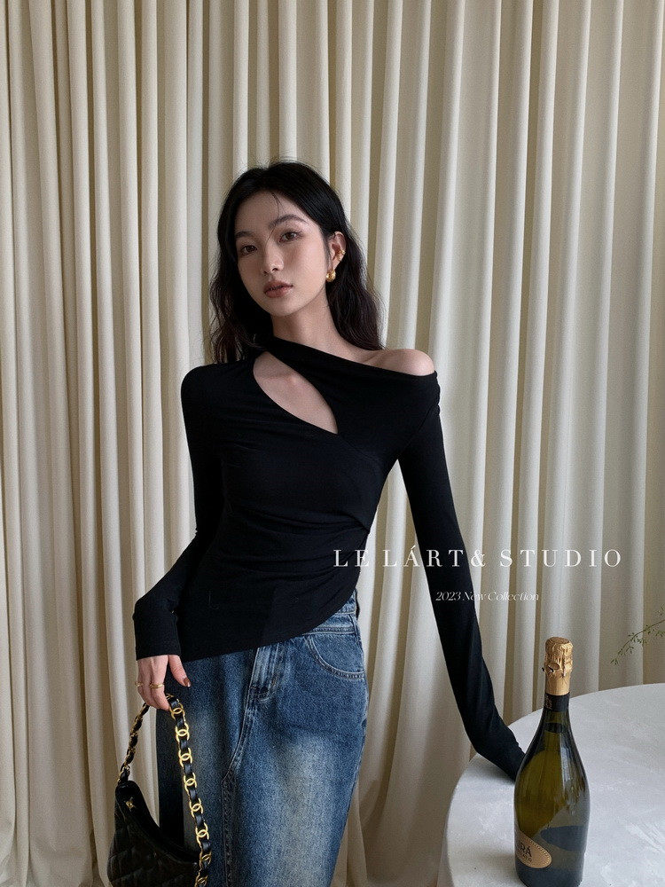 Black asymmetrical long-sleeve top worn with jeans on a model