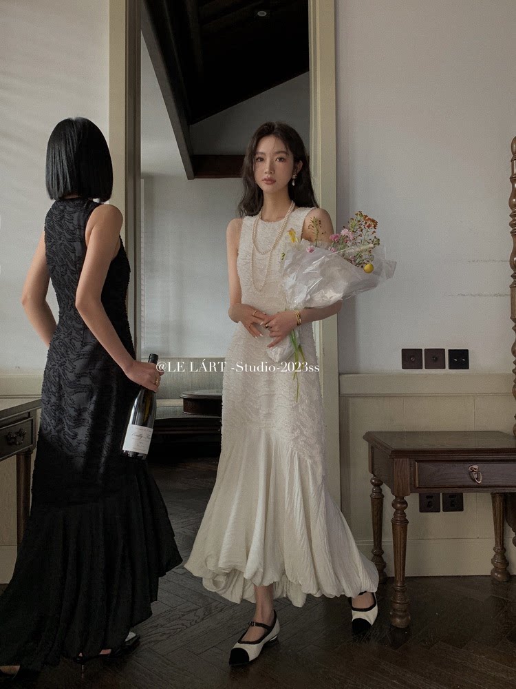 Two women wearing long elegant dresses, one in black and one in white