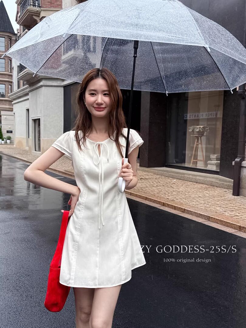 White short-sleeve mini dress worn by a woman holding a clear umbrella