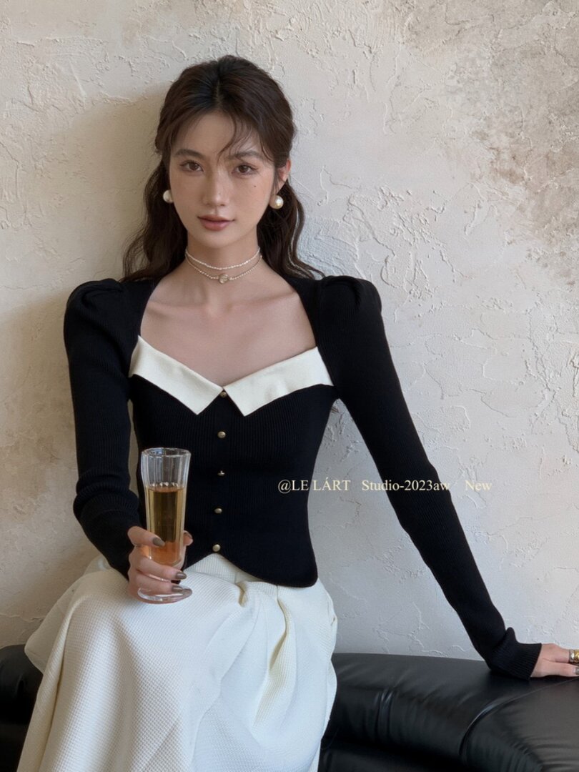 Model wearing a black and white fitted long-sleeve top with a white skirt
