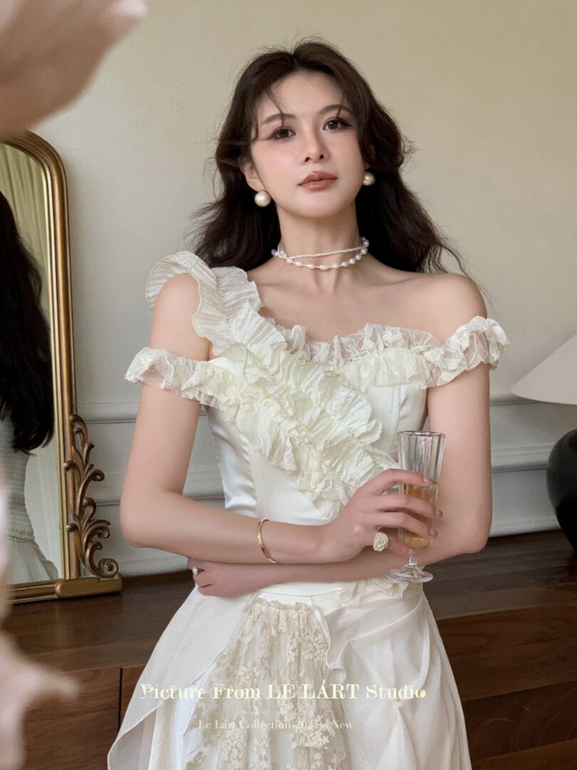 Woman wearing a white off-shoulder ruffled dress with pearl accessories