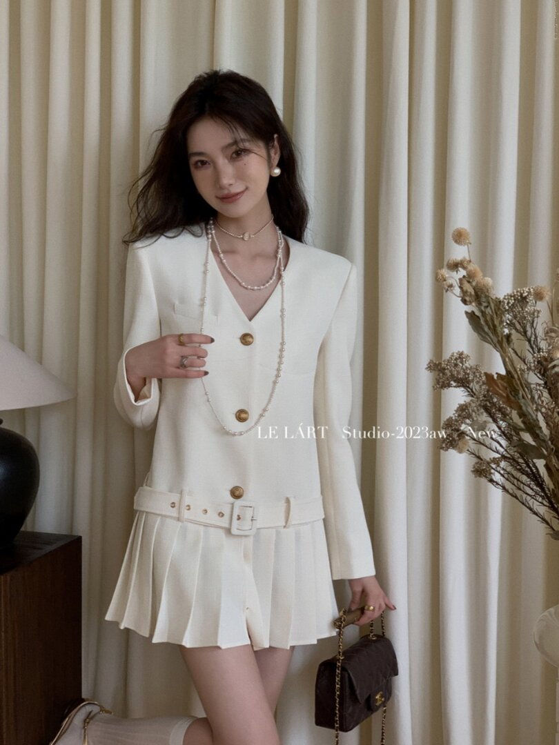 White blazer-style dress with belt and pleated skirt worn by a model