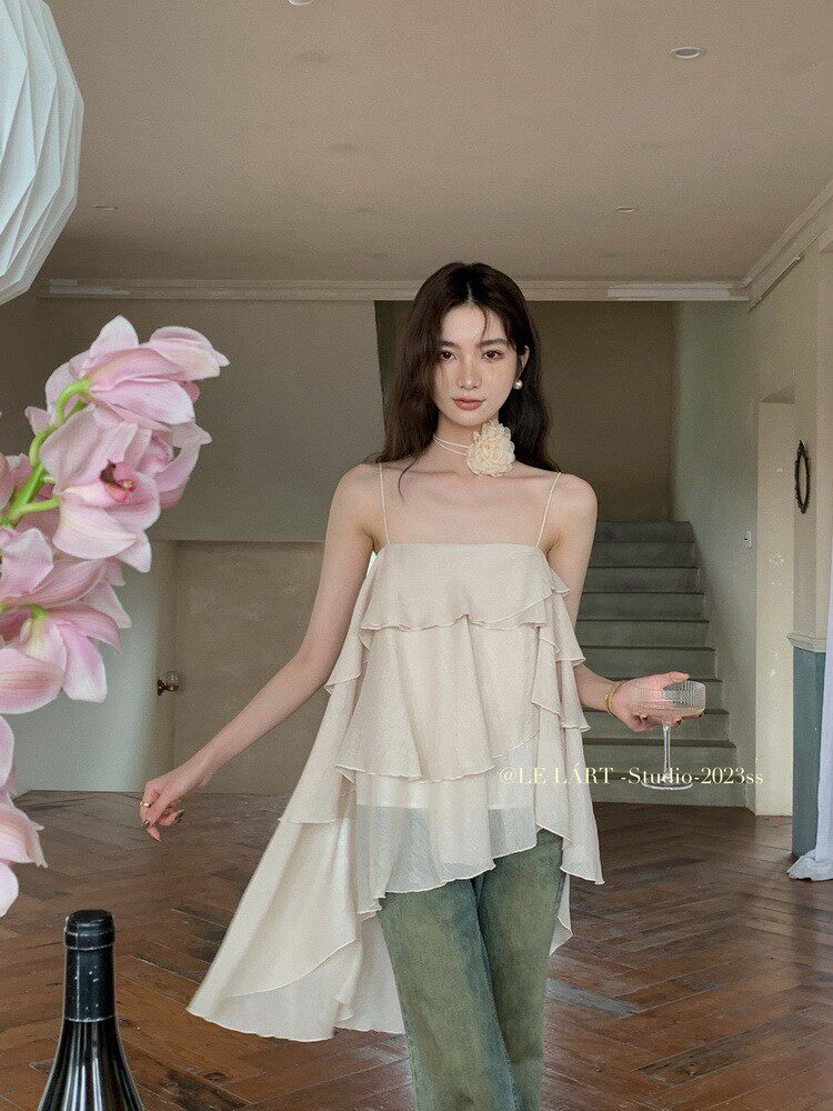 Model wearing a cream layered spaghetti-strap top with jeans
