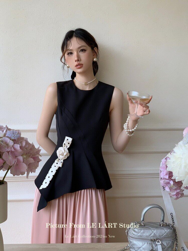 Black sleeveless peplum-style top worn with a pink skirt on a model