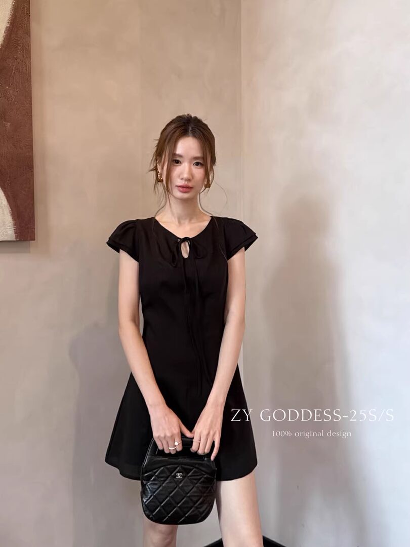 Black short-sleeve mini dress worn by a model with a small black handbag