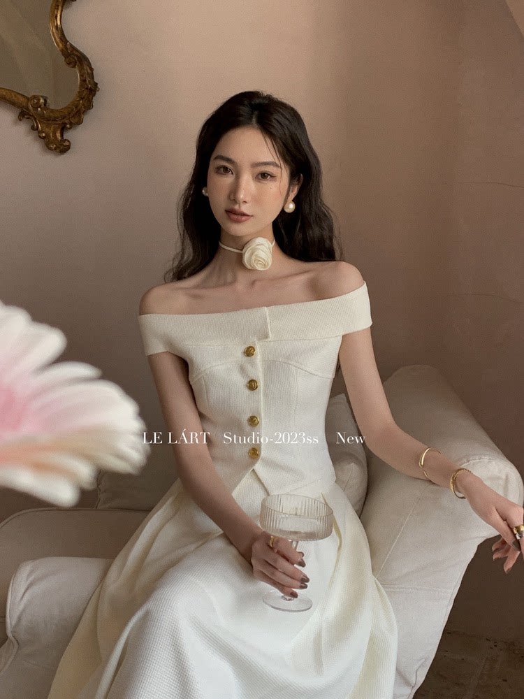 Woman wearing an off-shoulder white dress with gold buttons