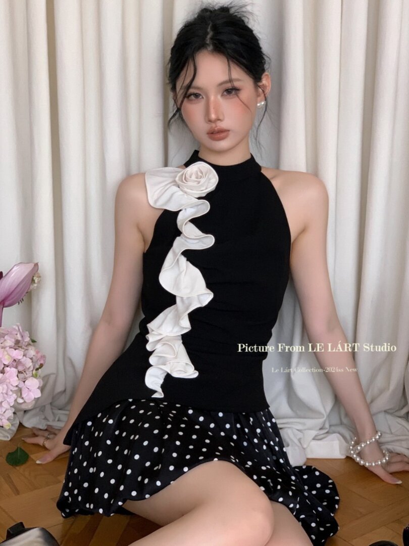 Black halter dress with a white ruffle detail and polka dot skirt worn by a model