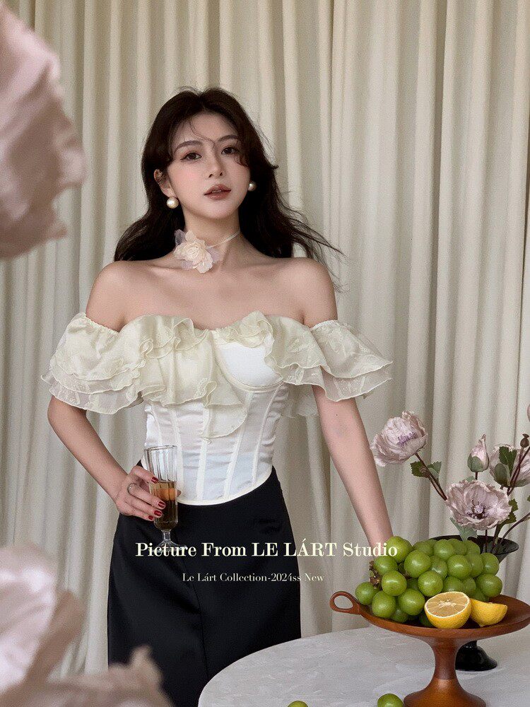 Woman wearing an off-shoulder ruffled corset-style top with black pants