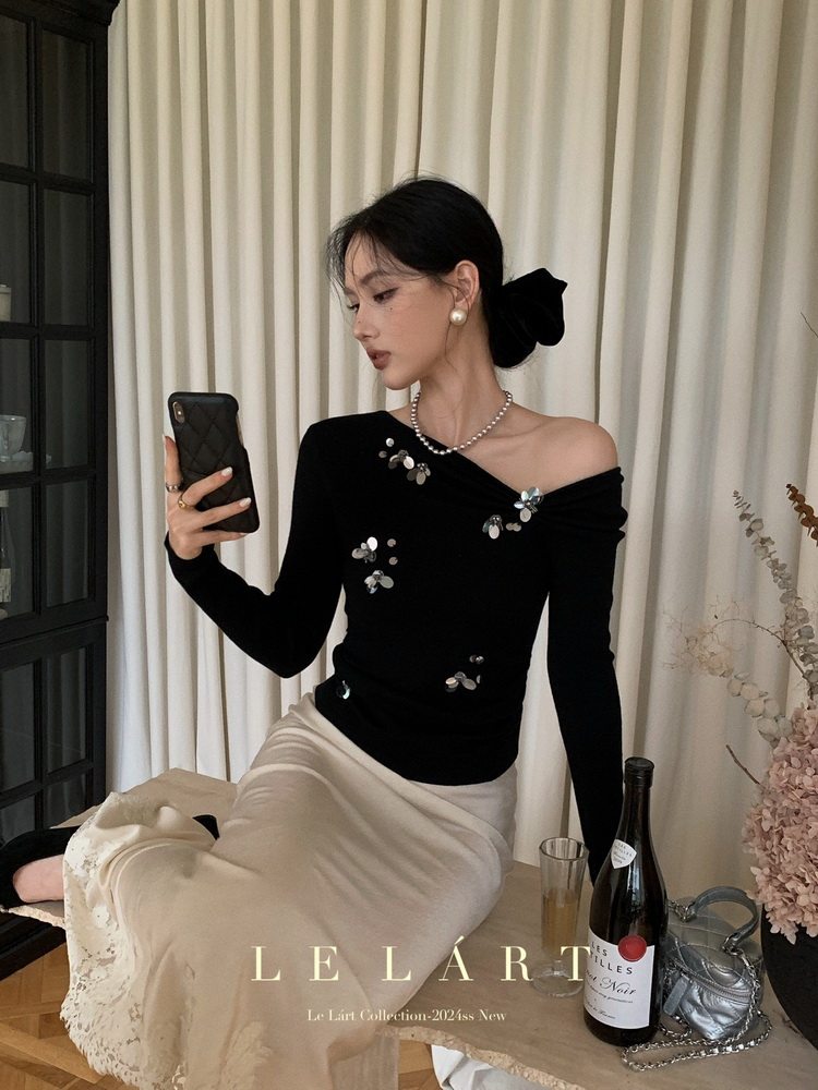 Model wearing a black off-shoulder embellished top with a cream skirt