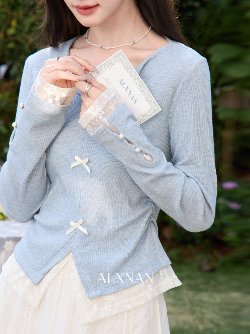 Light blue long-sleeve top worn by a model with lace cuffs and ribbon bows