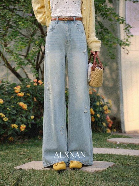 Model wearing light wash wide-leg jeans with a white polka dot top and yellow cardigan