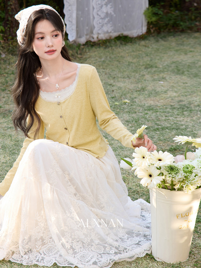 Model wearing a pastel yellow cardigan and white lace skirt outdoors
