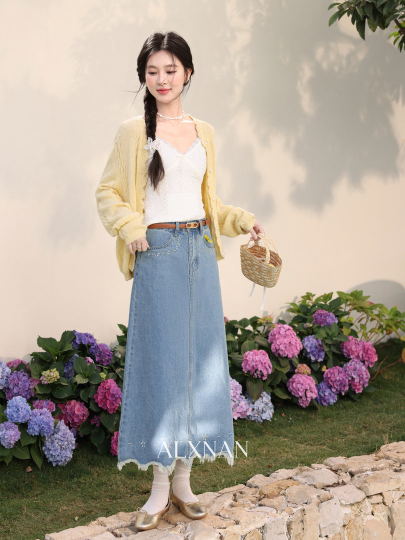 Model wearing a yellow cardigan, white camisole, and denim maxi skirt outdoors