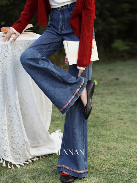 Model wearing wide-leg blue denim jeans with a red cardigan outdoors