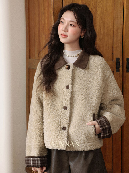 Model wearing a beige teddy shearling jacket with plaid cuffs and brown collar