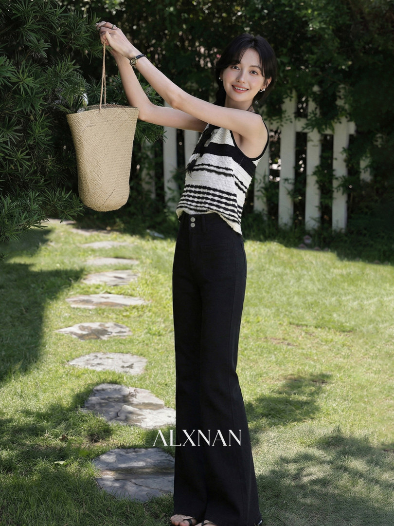 Model wearing a black-and-white striped sleeveless top with black wide-leg pants and a straw tote bag