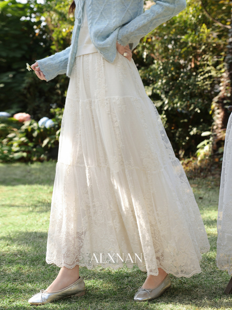 Woman wearing a cream lace midi skirt with a light blue cardigan and silver flats outdoors