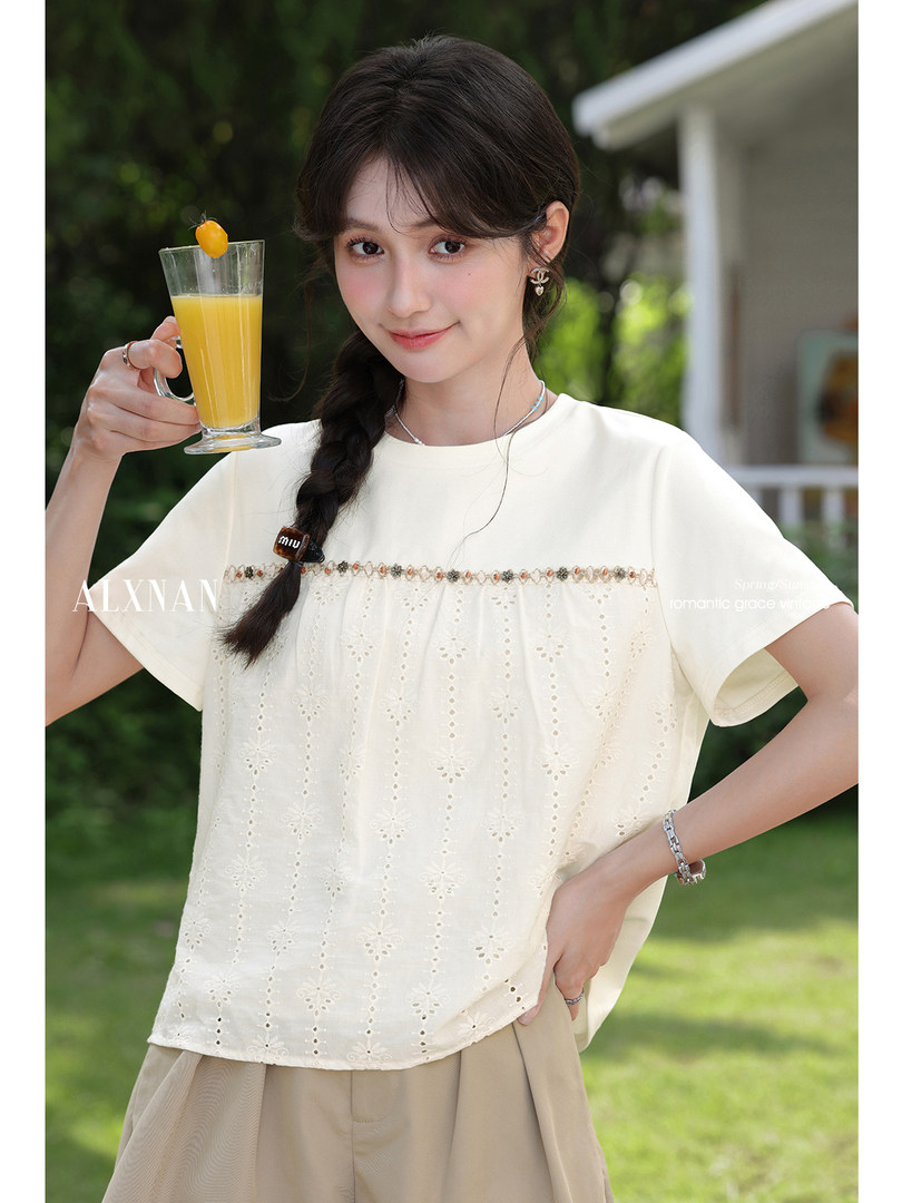 Model wearing a cream embroidered short-sleeve top outdoors