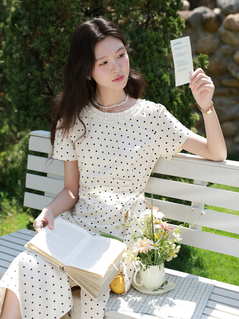 White polka dot dress worn by a woman outdoors on a bench